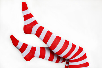 Female legs in Christmas knee socks on white background. Concept of New Year celebration, woman in stockings with red and white stripes
