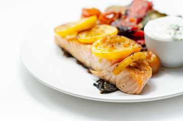 Grilled salmon fillet served with roasted vegetables with cucumber and dill sauce