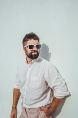 Handsome beard man posing in the street, near with wall, sunglasses, hipster style, outdoor portrait, fashion model, happy face, 