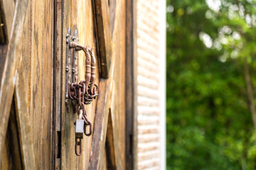 Close-up at rustic chain and keypad that locking on wooden gate of the farmhouse or barn entrance. Object and building, selective focus.