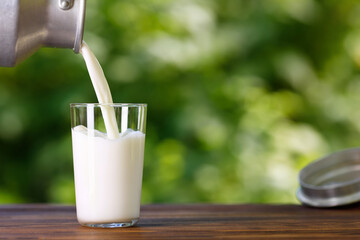 milk pouring from metal can into glass