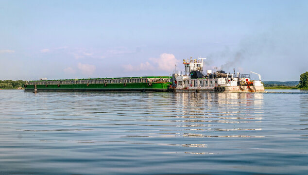 River barge and tugboat carrying cargo on the river
