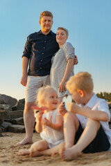 lovely caucasian family with mom expecting child enjoy sunset on beach