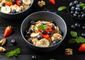 Healthy Oatmeal porridge breakfast with strawberry, blueberry, banana and honey