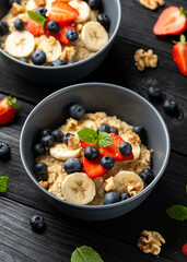 Healthy Oatmeal porridge breakfast with strawberry, blueberry, banana and honey