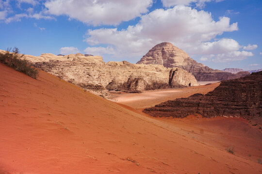 view of red relief mountains from a sand dune, blue sky with beautiful white clouds, Wadi Rum desert, nature of Jordan