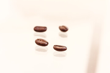 Macro of four roasted brown coffee beans  and their reflection on glass  background. Side view,  copy space