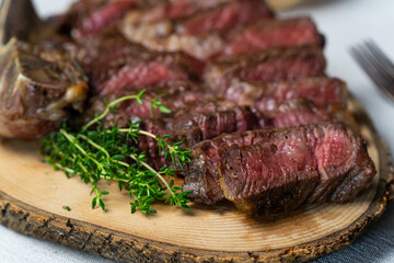 Sliced medium rare grilled beef steak on wooden cutting board with spices