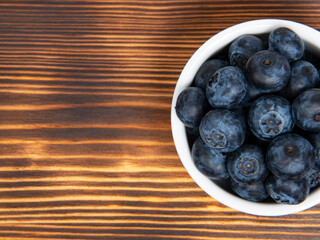 Fresh blueberry in white dish on wooden background