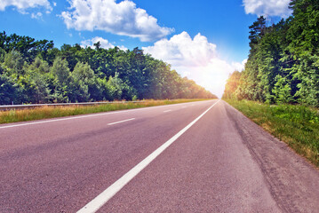 Highway leading to the sun among the trees in summer