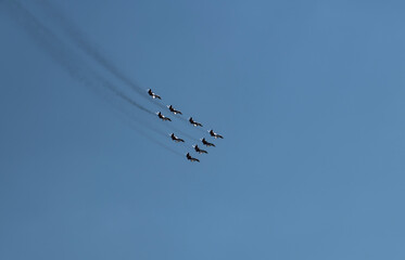 nine combat aircraft perform complex aerobatics against the sky 