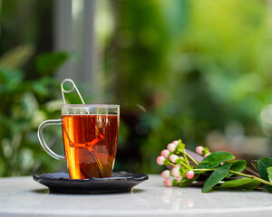 cup of fresh aromatic tea on table with nature flowers background