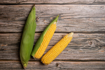 Fresh corn cobs on flat wooden background