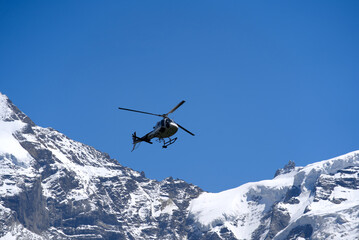 Fototapeta na wymiar White transport helicopter at Lauterbrunnen on a sunny summer day with Jungfraujoch in the background. Photo taken July 20th, 2021, Lauterbrunnen, Switzerland.