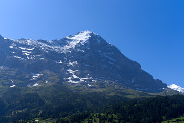 Mountain peak Eiger at Bernese highland on a sunny summer day with blue sky background and clouds...