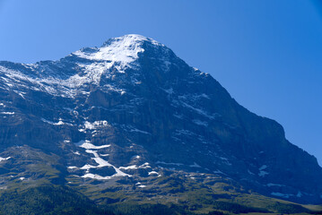 Mountain peak Eiger at Bernese highland on a sunny summer day with blue sky background and clouds in the foreground. Photo taken July 20th, 2021, Lauterbrunnen, Switzerland.