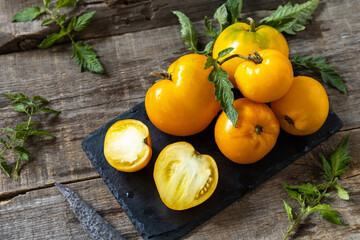 Fresh healthy raw ripe organic yellow tomatoes on a kitchen wooden table.