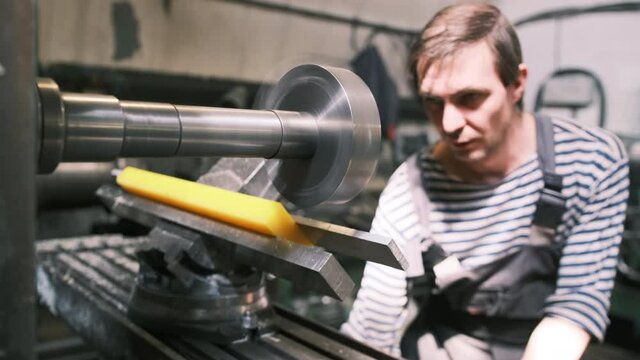 Front view. A worker in production processes a polyurethane part on a horizontal milling machine. A milling cutter at a polyurethane products manufacturing plant makes an order according to drawings