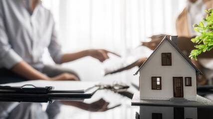 House model with agent and customer discussing for contract to buy, get insurance or loan real...
