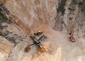 Arial view of the open pit mine. Front end loader loading gravel into stone jaw crusher in...