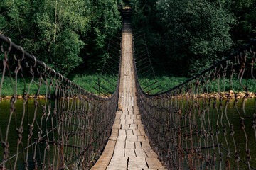 old suspension bridge over the river goes into perspective