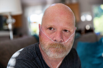 Old man with oxygen tank hose in nose battling medical condition in lungs - Covid-19 pneumonia