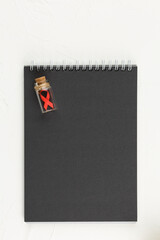 Black notepad with red ribbon as sign of cancer.