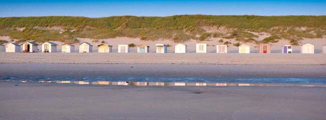 beach huts on dutch wadden island of texel at dusk under blue sky in summer - obrazy, fototapety, plakaty