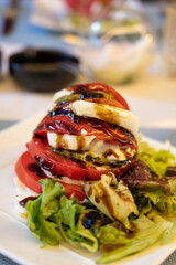 Big red french tomato served with fresh mozzarella cheese, basil pesto and creme balsamico as starter in restaurant in Provence, France