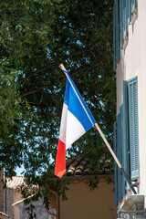 Walking on ancient french village Grimaud, French flag,  touristic destination with ruines fortress castle on top, Var, Provence, France