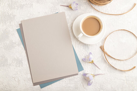 Gray paper sheet mockup with spring snowdrop crocus flowers and cup of coffee on gray concrete background. top view, copy space, close up.