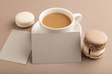 Gray paper business card mockup with brown and white macaroons and cup of coffee on beige pastel...