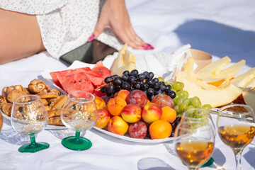 Fruit and wine on the tablecloth, next to a girl and a telephone (picnic).