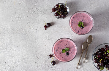 Natural yogurt with black currant in two glass on light gray background. Top view. Space for text