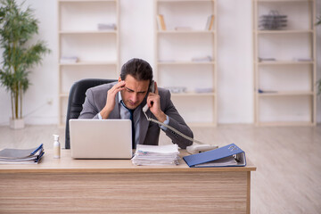 Young male employee unhappy with excessive work in the office