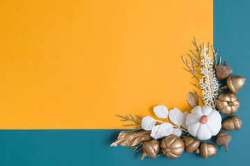 Still life of golden acorns, leaves and pumpkins on an orange-turquoise background. Minimalistic autumn concept with copy space