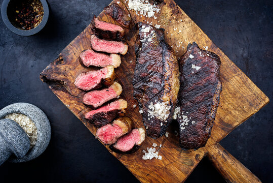 Traditional barbecue dry aged wagyu Brazilian picanha steaks from the sirloin cap of rump beef sliced and served as top view on a rustic wooden board