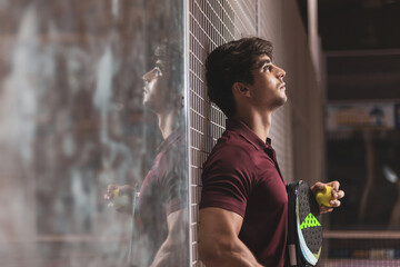  a young paddle tennis player resting leaning against the wall while thinking about his victory. winner, paddle competition. ©  Yistocking