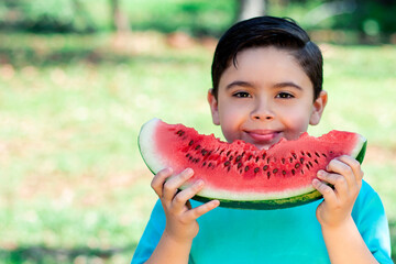 child holds watermelon, healthy portrait with nature in the background and sunlight