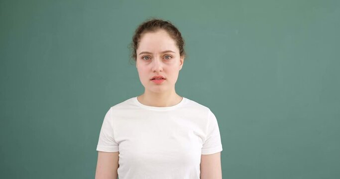 A young girl speaks no way and gestures. Colored background, white t-shirt.