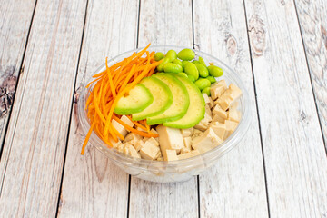 Vegan bowl of Hawaiian poke with slices of Mexican avocado, Japanese edamame beans, grated carrots...