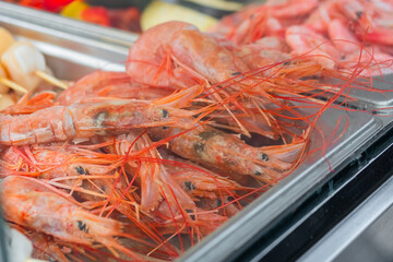 Cooked fresh red langoustine shrimps, prawns in restaurant food container at summer local market - close up. Outdoor cooking, gastronomy, seafood, takeaway, street food concept
