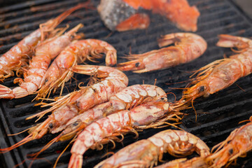 Process of cooking fresh red langoustine shrimps, prawns on grill at summer local food market - close up. Outdoor cooking, barbecue, gastronomy, seafood, cookery, street food concept