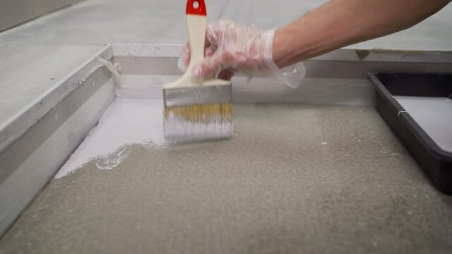 The process of priming the floor with white paint. The master applies white waterproofing to the floor.