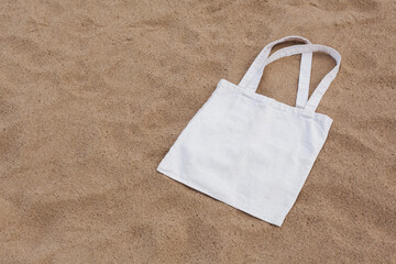White cotton or mesh bag on beach sand background. Zero waste, no plastic, eco friendly shopping,...