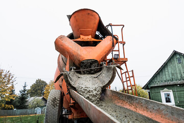 The concrete mixer unloads the concrete through a chute into a prepared container at the...