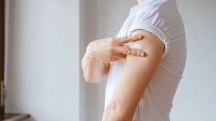 Unrecognized Vaccinated Man Showing Arm With Medical Patch Plaster After Covid-19 Vaccine Injection. Coronavirus Vaccination Advertisement Campaign. Vaccine Sign Done
