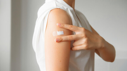 Unrecognized Vaccinated Woman Showing Arm With Medical Patch Plaster After Covid-19 Vaccine Injection. Coronavirus Vaccination Advertisement Campaign. Vaccine Sign Done