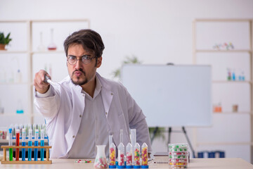 Young male chemist in drugs synthesis concept