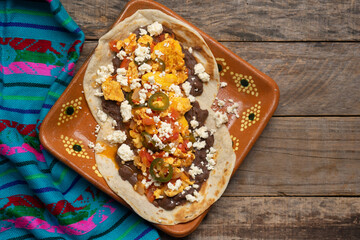Mexican eggs with refried beans and cheese on wooden background.